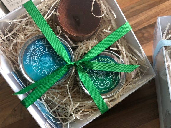 Gift box with clear lid showing seasonings and a wooden pinch pot with ribbon tie