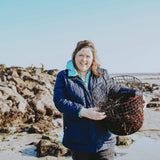 Image of Naomi holding a basket of cut seaweed on the beach