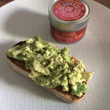 Tin of chilli seaweed salt next to a piece of toast with crushed avocado sprinkled with chilli seaweed salt