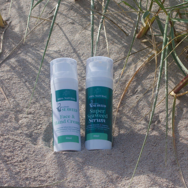 Two bottle on the beach. Super Seaweed Serum and Face & Hand Cream. Made by Guernsey Seaweed