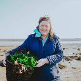 Naomi on the beach holding basket of cut seaweed