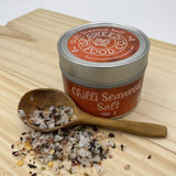 Tin of mild chilli seaweed salt on wooden board with a tiny wooden spoon and salt